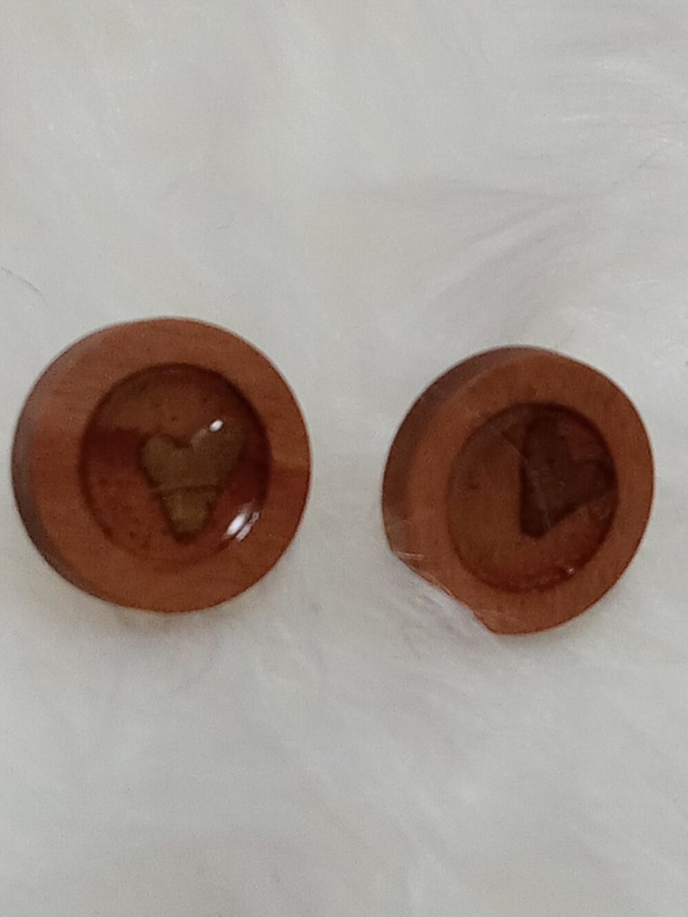 Handmade earrings on a wooden base with a piece of punched-out tree leaf